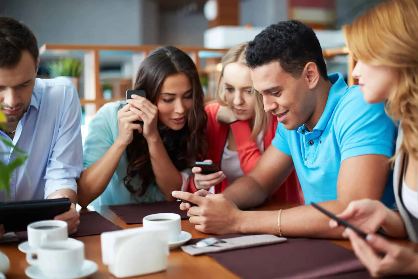 48853027 - young people sitting at cafe with mobile phones