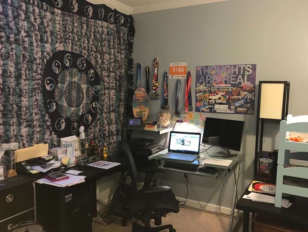 A home office environment with laptop, desk, and wall decorations.