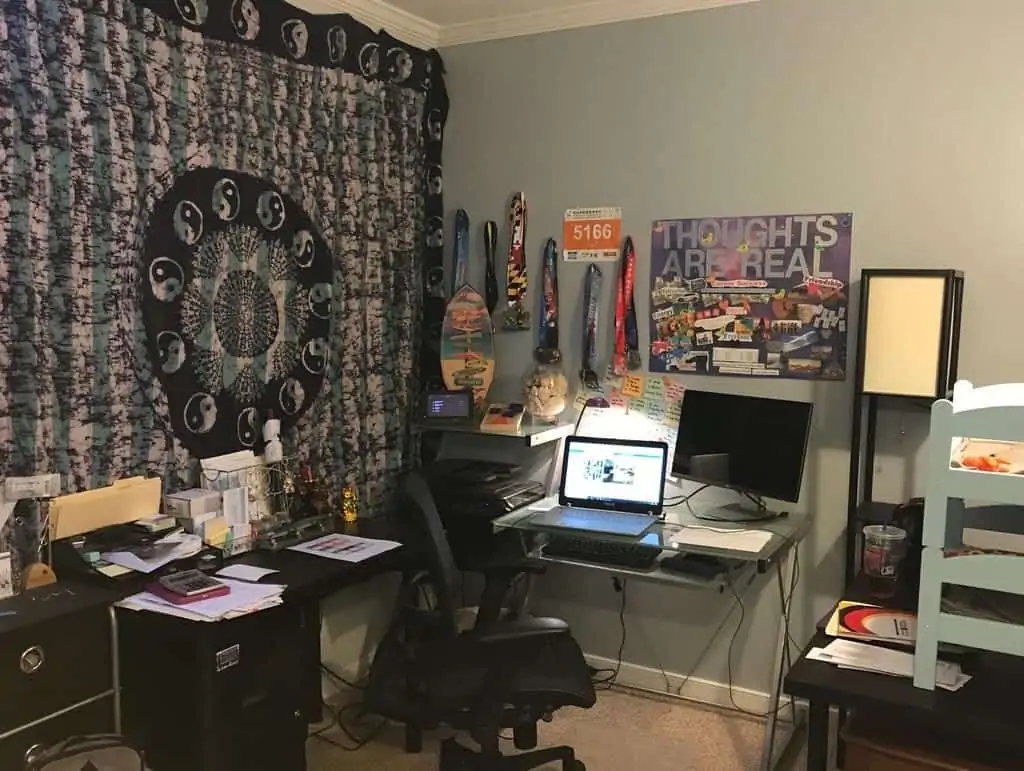 A home office environment with laptop, desk, and wall decorations.